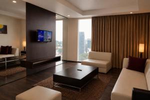 a living room with a couch and a tv at Akmani Hotel Jakarta in Jakarta