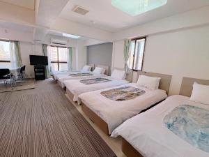 a hotel room with four beds and a television at Weekly Green In Namba in Osaka
