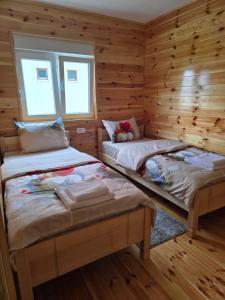 two beds in a log cabin with two windows at Mountain House 22 in Žabljak