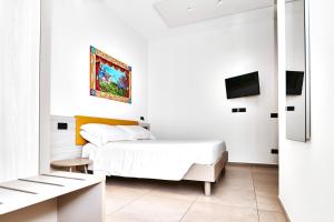 a white bedroom with a bed and a tv at MARINO WELLNESS in Alì Terme