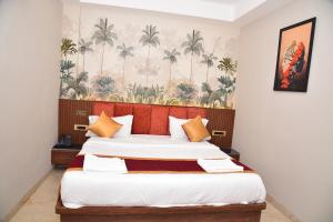 a bedroom with two beds and a wallpaper with palm trees at HOTEL THIRD EYE bY RAMANA TOWERS in Tiruvannāmalai