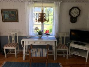 a dining room with a table and chairs and a clock at Sjöberg's Cosy Cottage in Ljungby