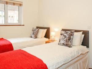 a bedroom with two beds and a red blanket at Ash Cottage in Uckfield