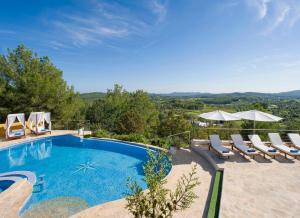a swimming pool with lounge chairs and a view of the mountains at Villa Buscastells in Santa Gertrudis de Fruitera