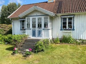a small white house with a porch and stairs at Sjöberg's Cosy Cottage in Ljungby