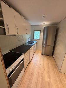 a kitchen with a stainless steel refrigerator and wooden floors at Detached cozy house in Lom