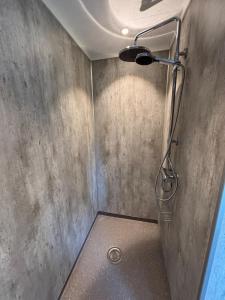 a shower in a bathroom with a concrete wall at Detached cozy house in Lom +1 photo