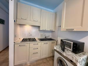 a kitchen with white cabinets and a sink and a microwave at Condominio Vera Cruz in Bibione