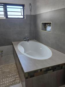 a large white tub in a bathroom with a window at Ednomis Apartment in Mazabuka