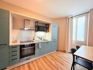 a kitchen with blue cabinets and a table and a window at L'instant à Foix - Authentique & Chaleureux in Foix