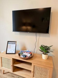 a flat screen tv on a wall above a wooden table at L'instant à Foix - Authentique & Chaleureux in Foix +10 photos
