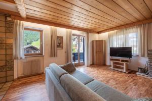 a living room with a couch and a flat screen tv at Alpen Suite Apartment in San Vigilio Di Marebbe