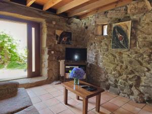 a living room with a stone wall with a tv and a table at Villa Vetusta in Penso