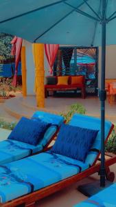 two beds sitting under an umbrella on a patio at Villa Symphonie Saly in Saly Portudal