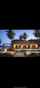 a large house with palm trees in the background at Corniche inn river view villa 2 BHK in Kāsaragod