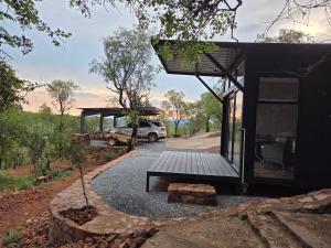 a house with a porch and a car parked next to it at Lazy Hill Eco Lodge in Warmbaths