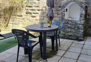 a black table with two chairs and an umbrella at L'aube de Vouglans 5 kms des plages in Pont-de-Poitte