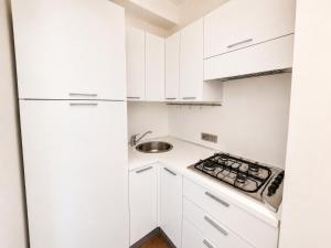 a white kitchen with white cabinets and a stove at Porta Nuova Studio - Sostify in Bergamo