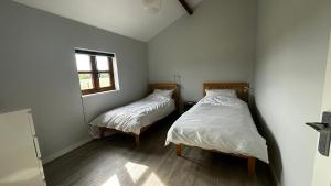 two beds in a small room with a window at Peacock Barn in Walsoken