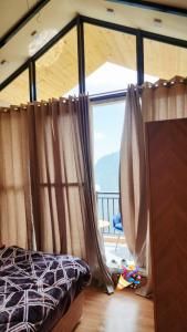 a bedroom with a bed and a large window at Hazy hill in Mussoorie