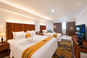 a hotel room with two beds and a flat screen tv at Metro Park View Hotel Kota Lama Semarang in Semarang