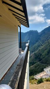 a balcony of a house with a view of the mountains at Hazy hill in Mussoorie