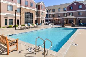 a swimming pool at a hotel with tables and chairs at Staybridge Suites O'Fallon Chesterfield by IHG in O'Fallon