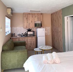 a room with a bed and a kitchen with a refrigerator at Urban Rest Guesthouse in Mahikeng