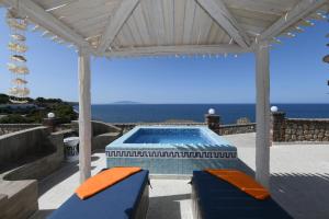 a swimming pool on a patio with the ocean in the background at Starlight Luxury Seaside Villa & Suites in Imerovigli