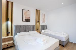 two beds in a room with white walls at Ionian View Rooms in Himare