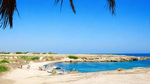 a group of people on a beach near the water at Pietra & Mare Ostuni in Villanova di Ostuni