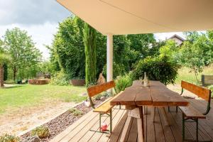 a wooden table and chairs on a deck with an umbrella at Plätzchen im Grünen in Owingen