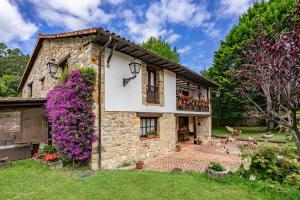 a stone house with flowers on the side of it at La Casa de Torre in Ribadesella