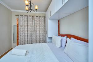a bedroom with a bed with white sheets and a window at 4 Bedroom Apartment Near JKIA & SGR in Nairobi