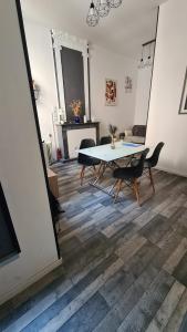 a dining room with a table and chairs on a wooden floor at Appart cosy avec balnéo, balcon, clim à 15 min de la Cité in Carcassonne
