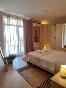 a bedroom with a large bed and large windows at Fole Maison in Durrës