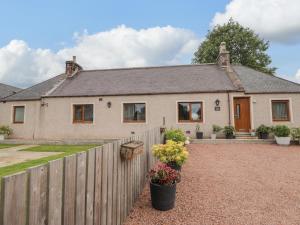 a house with a fence and flowers in front of it at Millmoss Cottage in Turriff