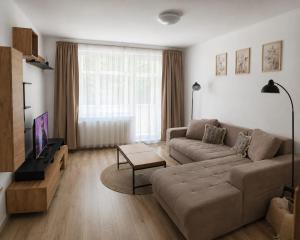 a living room with a couch and a tv at Hanga Apartman in Băile Tuşnad