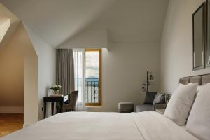 a bedroom with a bed and a chair and a window at Beau-Rivage Nyon in Nyon