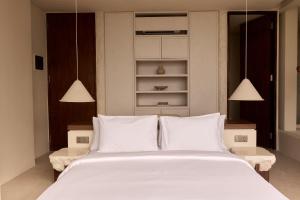a bedroom with a large white bed with white pillows at Fira Uluwatu in Uluwatu
