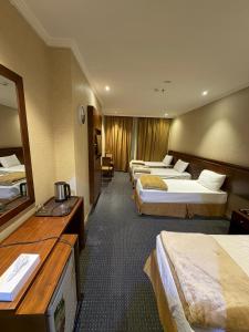 a hotel room with three beds and a desk at Al Maqam Alsharqy Shuttle Srevice to Haram in Mecca