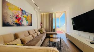 a living room with a couch and a flat screen tv at Veranda Apartment, Green Coast in Palasë