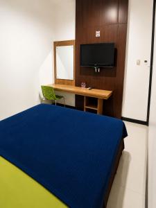 a bedroom with a bed and a desk and a television at Grand Kalimas Hotel in Surabaya