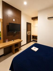a hotel room with a bed and a tv at Grand Kalimas Hotel in Surabaya