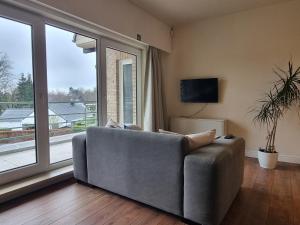 a living room with a couch and a large window at Ghent Business Flat in Ghent