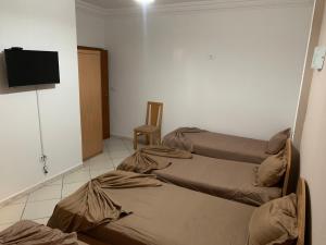 a room with two beds and a television on a wall at Montazah Residence in Dar el Koudia