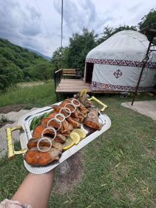 a person holding a tray of food on a table at SELKINCHEK resort in Kugart