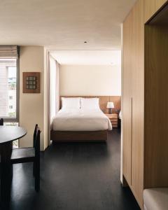 a bedroom with a bed and a table and a window at Long Weekend Haus in Seoul