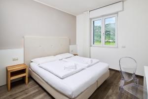 a white bedroom with a white bed and a window at Rolly - Rooms & Restaurant in Riva del Garda