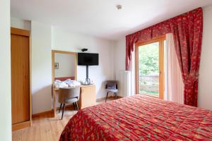 a hotel room with a red bed and a window at Garni Lago Nembia in San Lorenzo in Banale